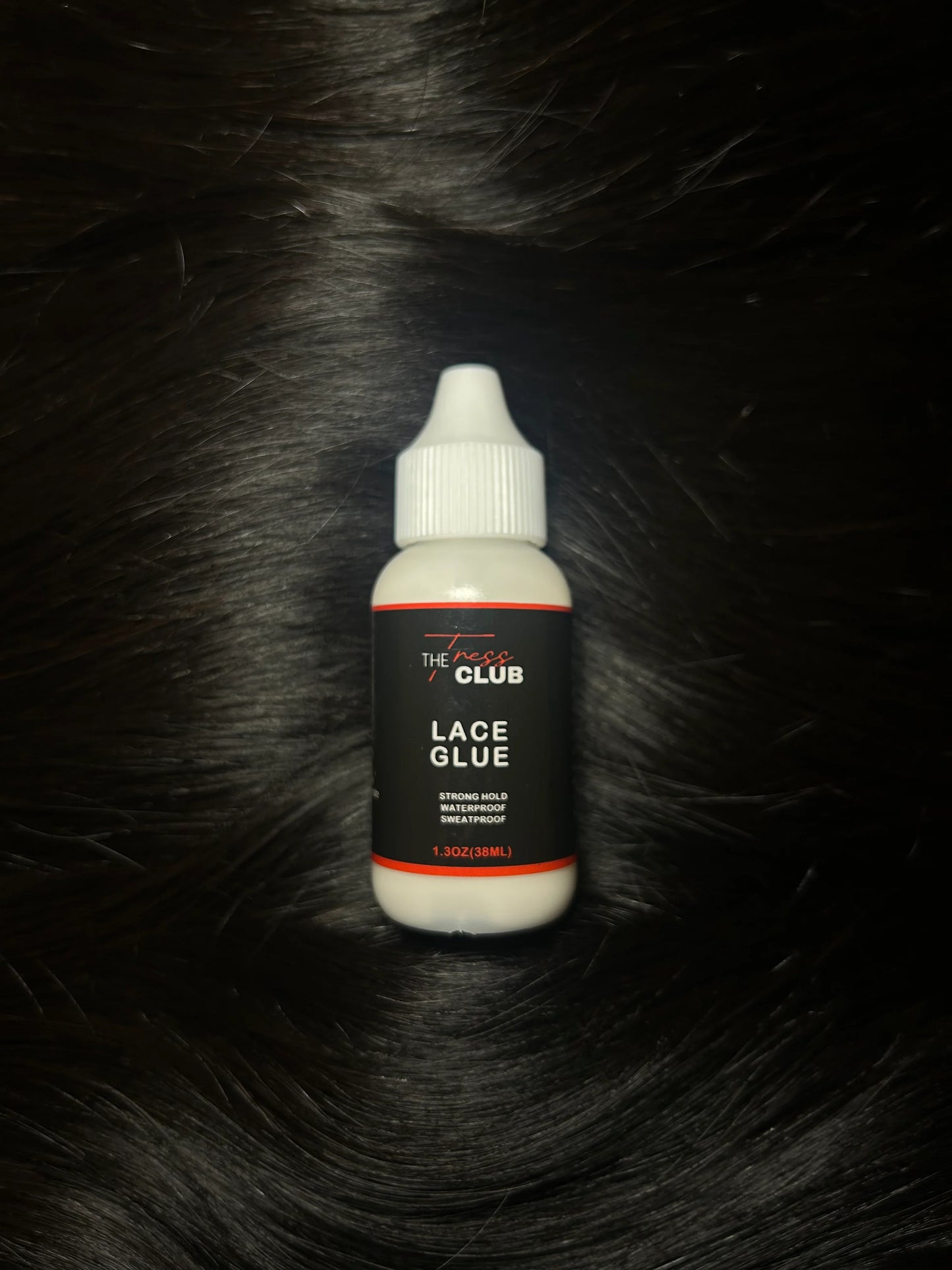 Lace glue bottle for wigs and hair extensions on black hair background