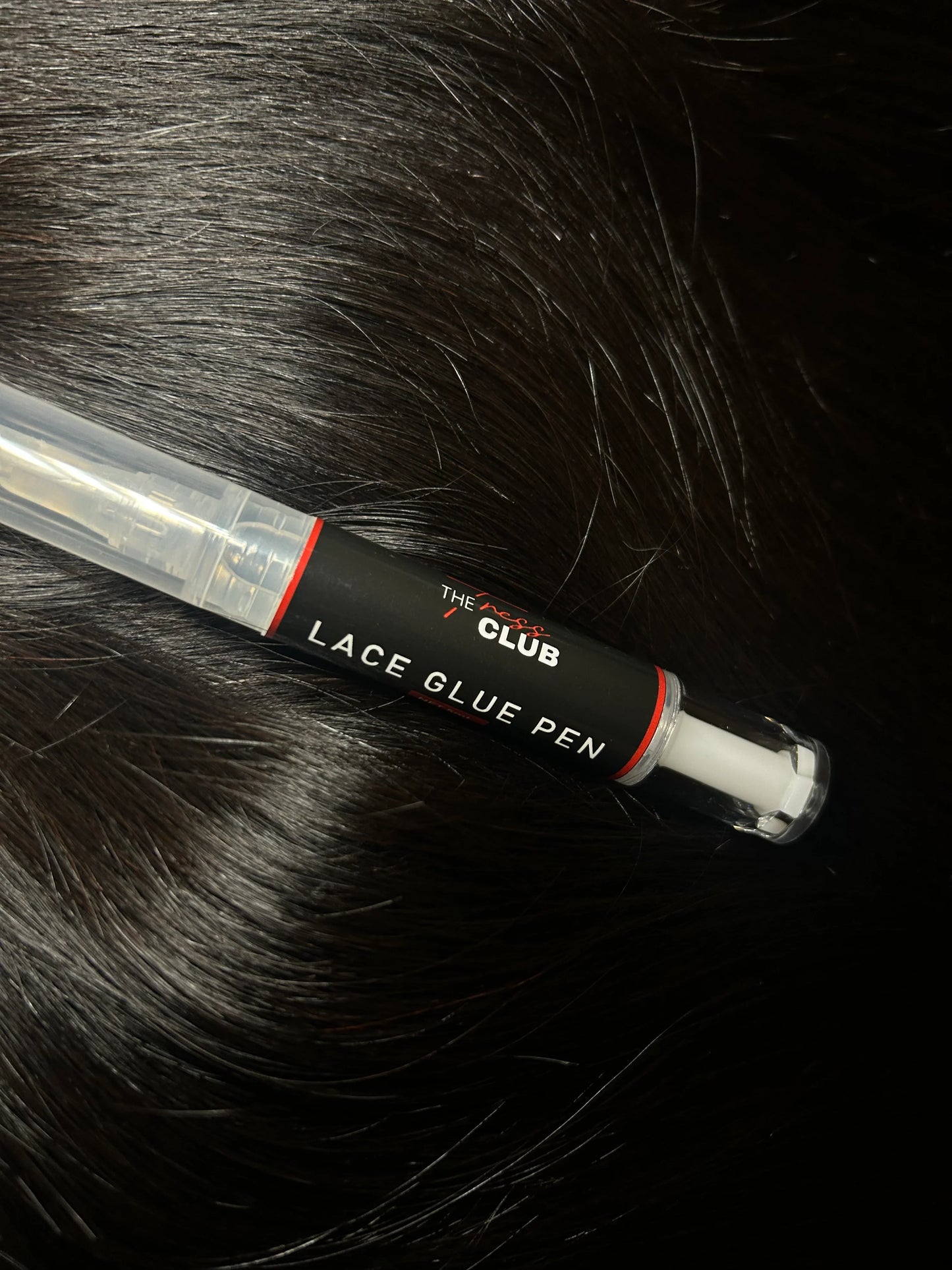 Lace glue pen for wigs and hair extensions on shiny black hair background
