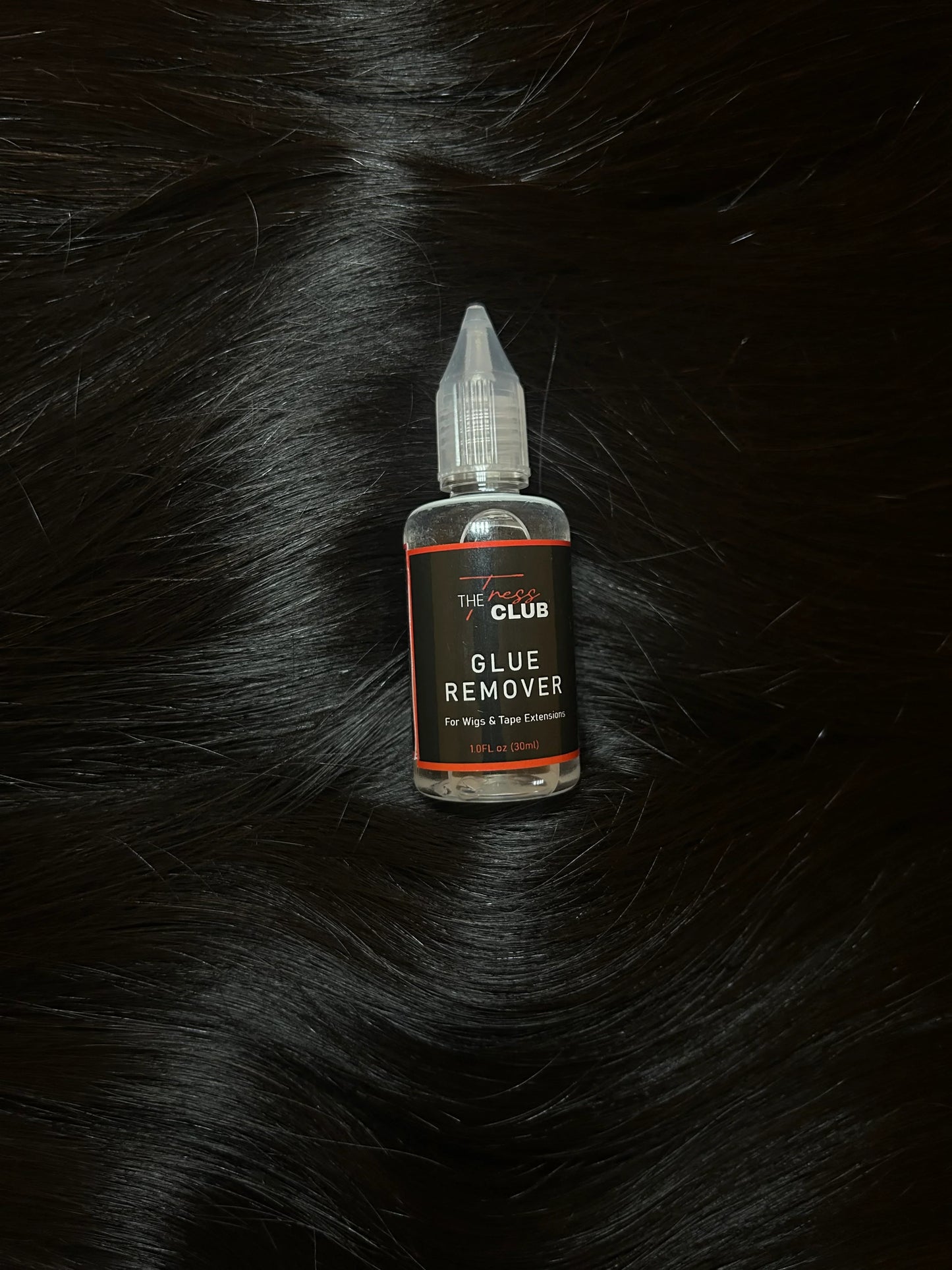 Glue remover bottle for wigs and tape extensions placed on black hair extensions