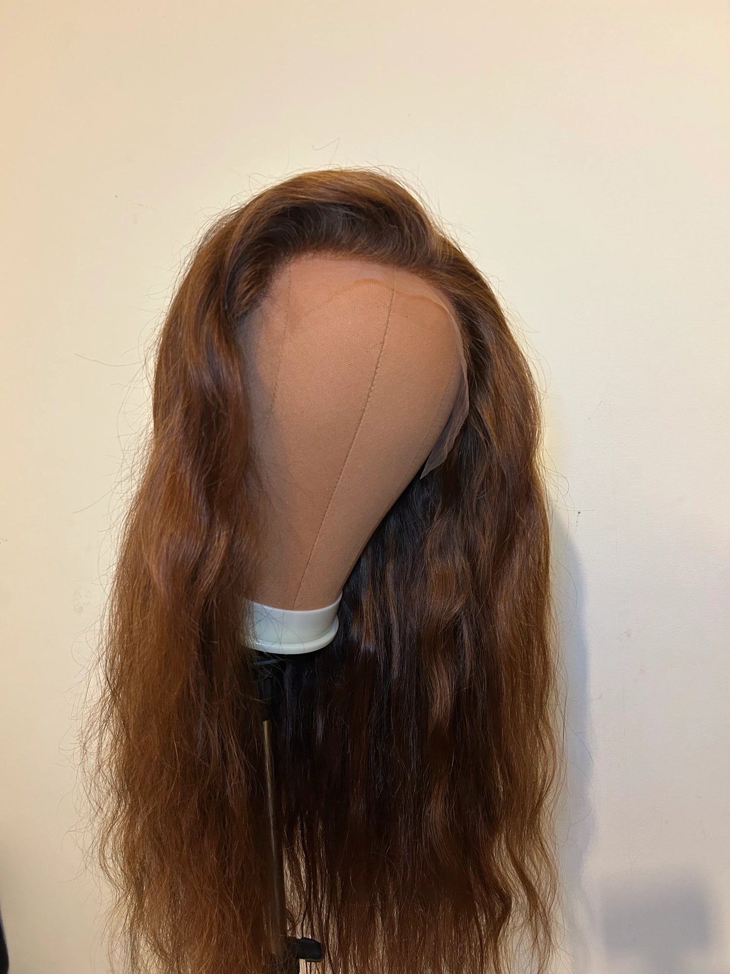Brown wavy lace front wig on mannequin head against plain background