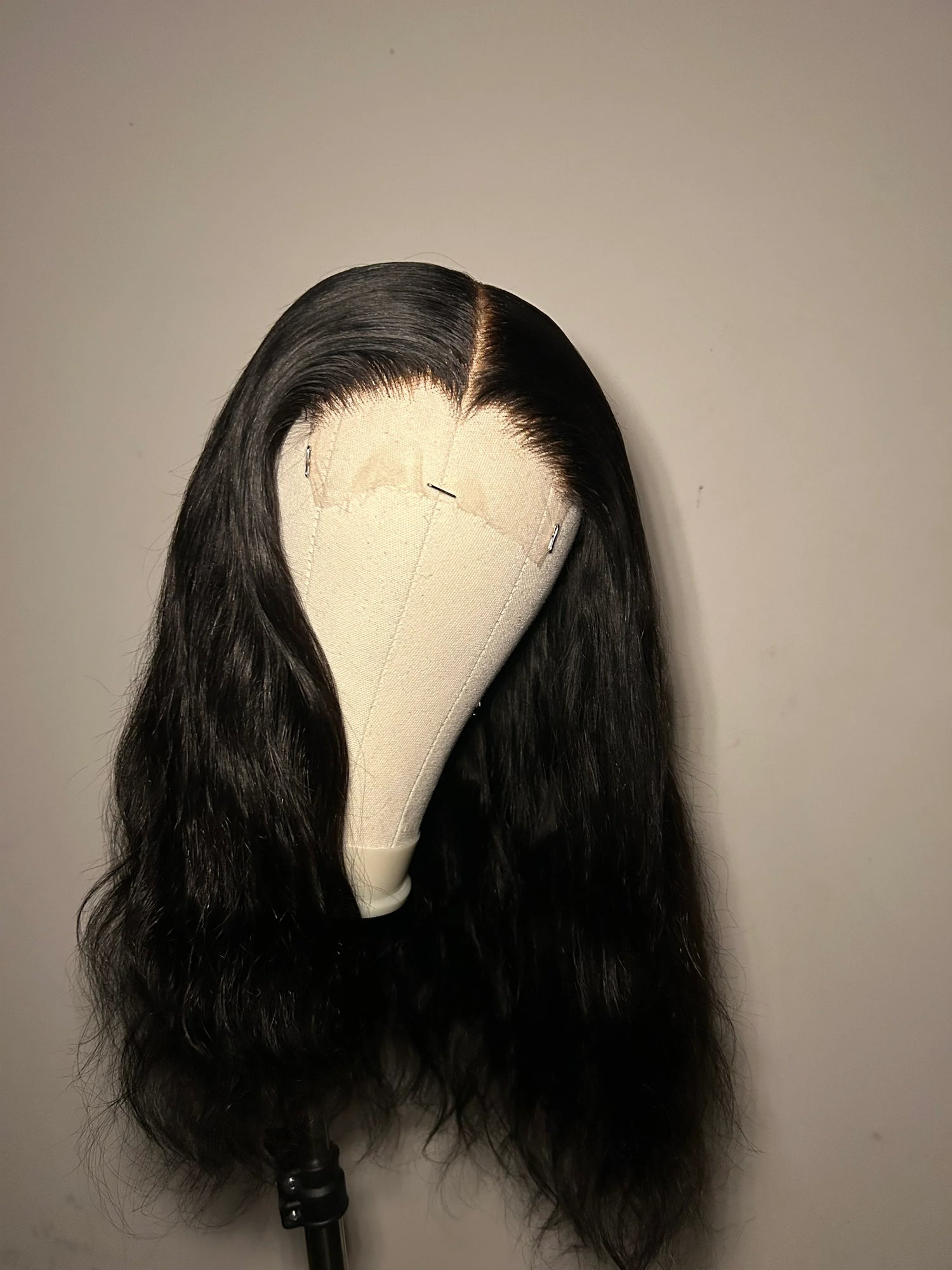 Natural wavy black lace front wig displayed on a mannequin head against plain background